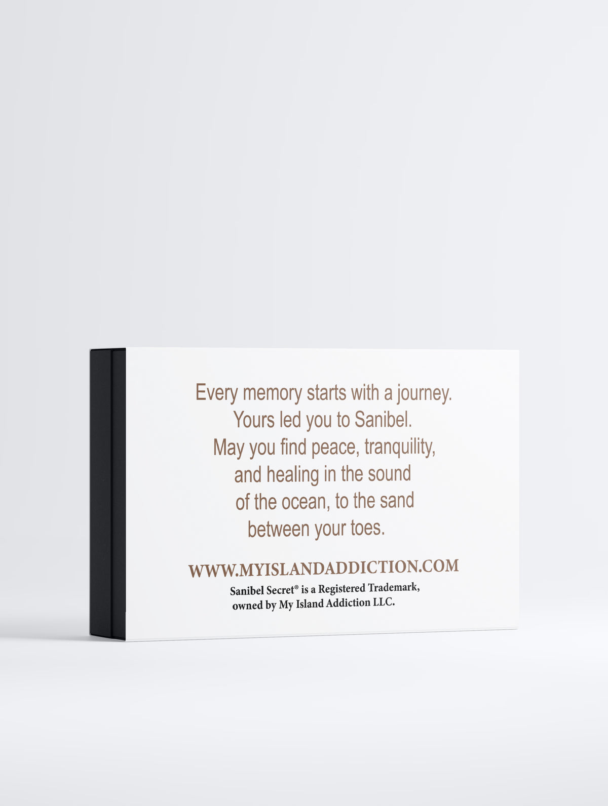 A rectangular white canvas print with black text, shown at a slight angle with a black side edge against a light gray background. The text references Sanibel and includes a website URL.